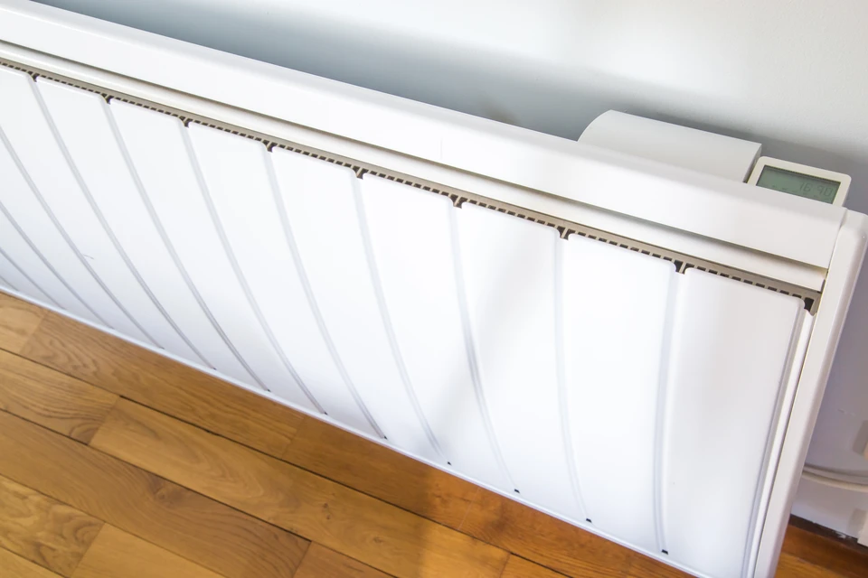 Intérieur résidentiel avec radiateur électrique blanc monté au mur, équipé d'un thermostat digital programmable