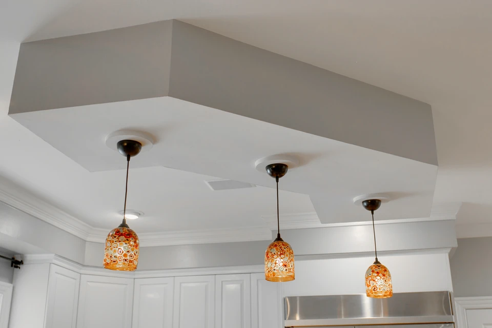Artisan électricien installant un luminaire suspendu dans cuisine moderne en rénovation