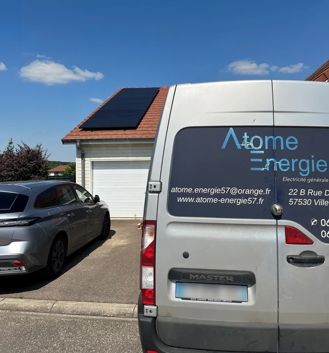 Deux techniciens installent des panneaux solaires photovoltaïques sur une toiture en tuiles sous ciel bleu